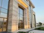 Marjan Silver Travertine facade design with tall windows and warm architectural lighting.