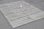 Polished Marjan Silver Travertine tiles laid out to show their parallel silver-gray veins.
