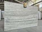 Marjan Silver Travertine slab showing layered gray and white veining in a stone warehouse.